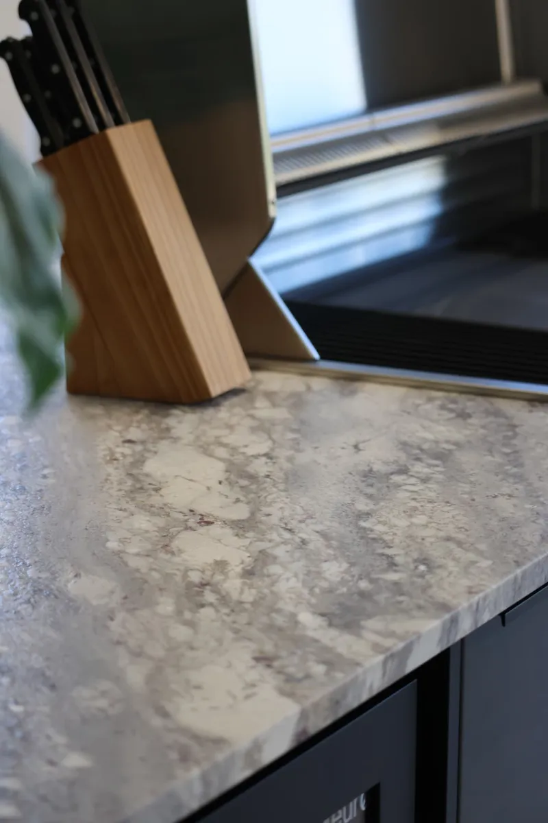Close-up of a stone benchtop finish with timber knife block detail
