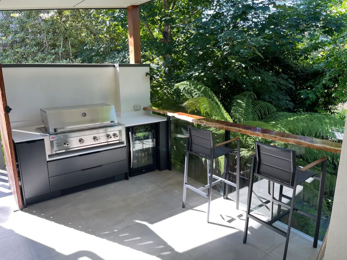 Completed custom outdoor kitchen installation with built-in BBQ, bar fridge and bar seating