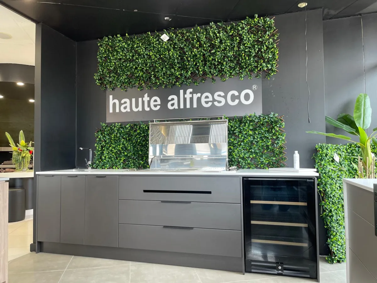 Haute Alfresco showroom display kitchen with grey cabinetry, built-in BBQ and wine fridge against a living green wall