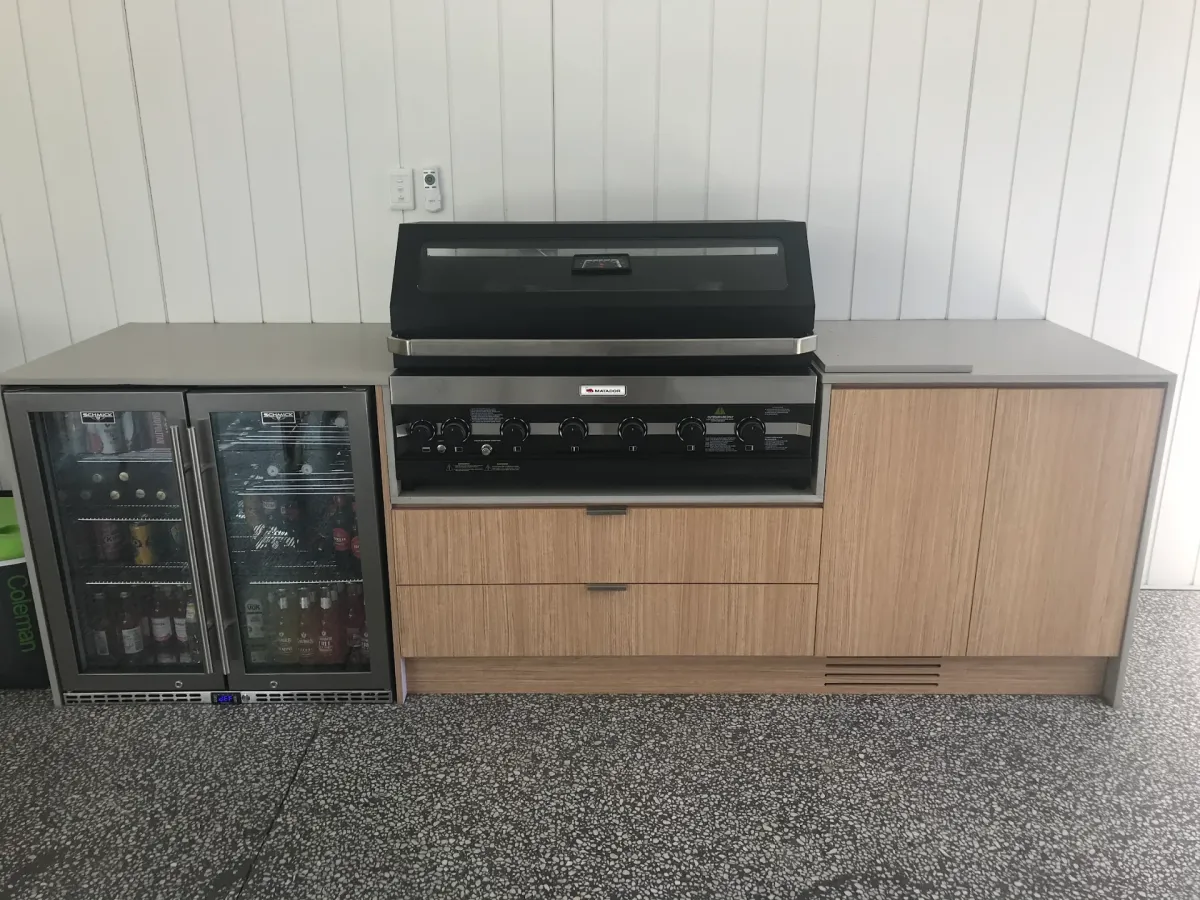 Custom outdoor kitchen with black BBQ, timber-look cabinetry and under-bench fridges